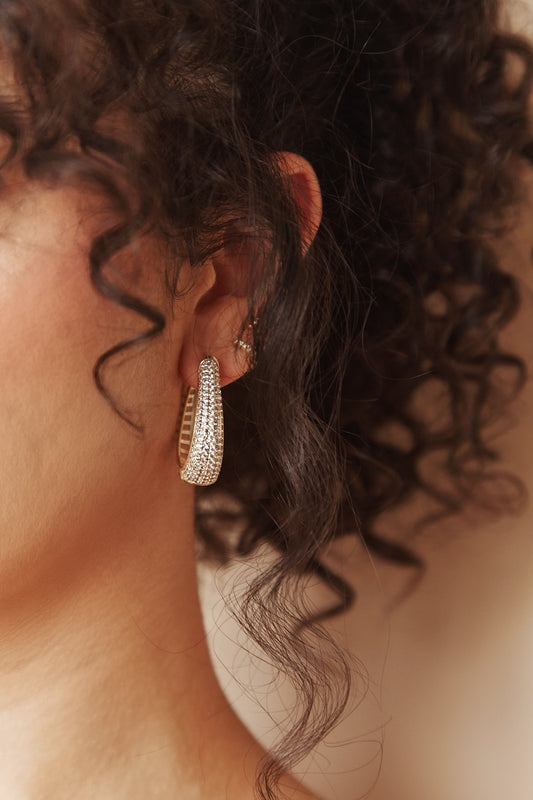 Model with curly hair wearing gold filled hoop earrings with cubic zirconia, worn in full double style